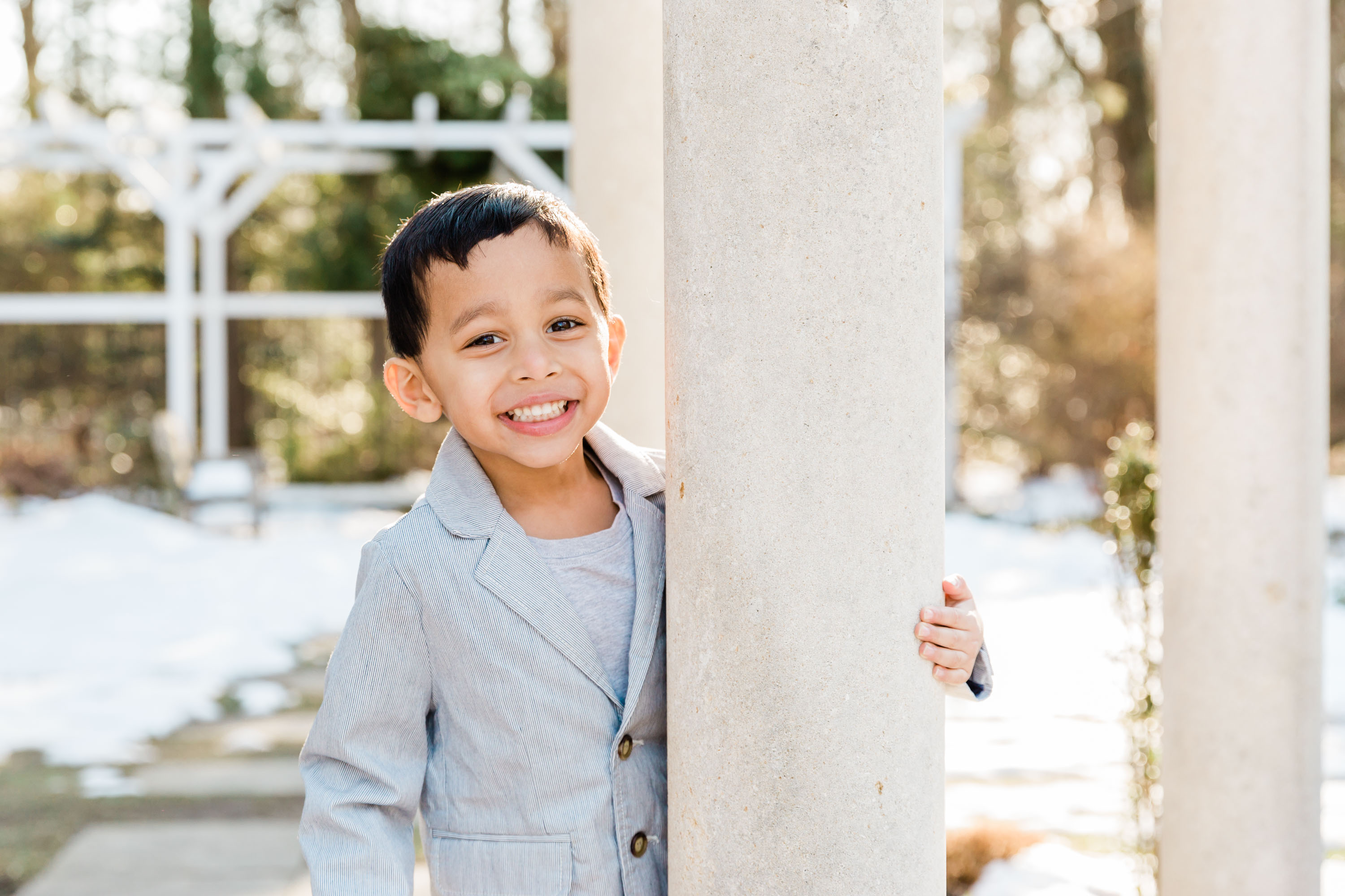 handsome little boy smiling beside column