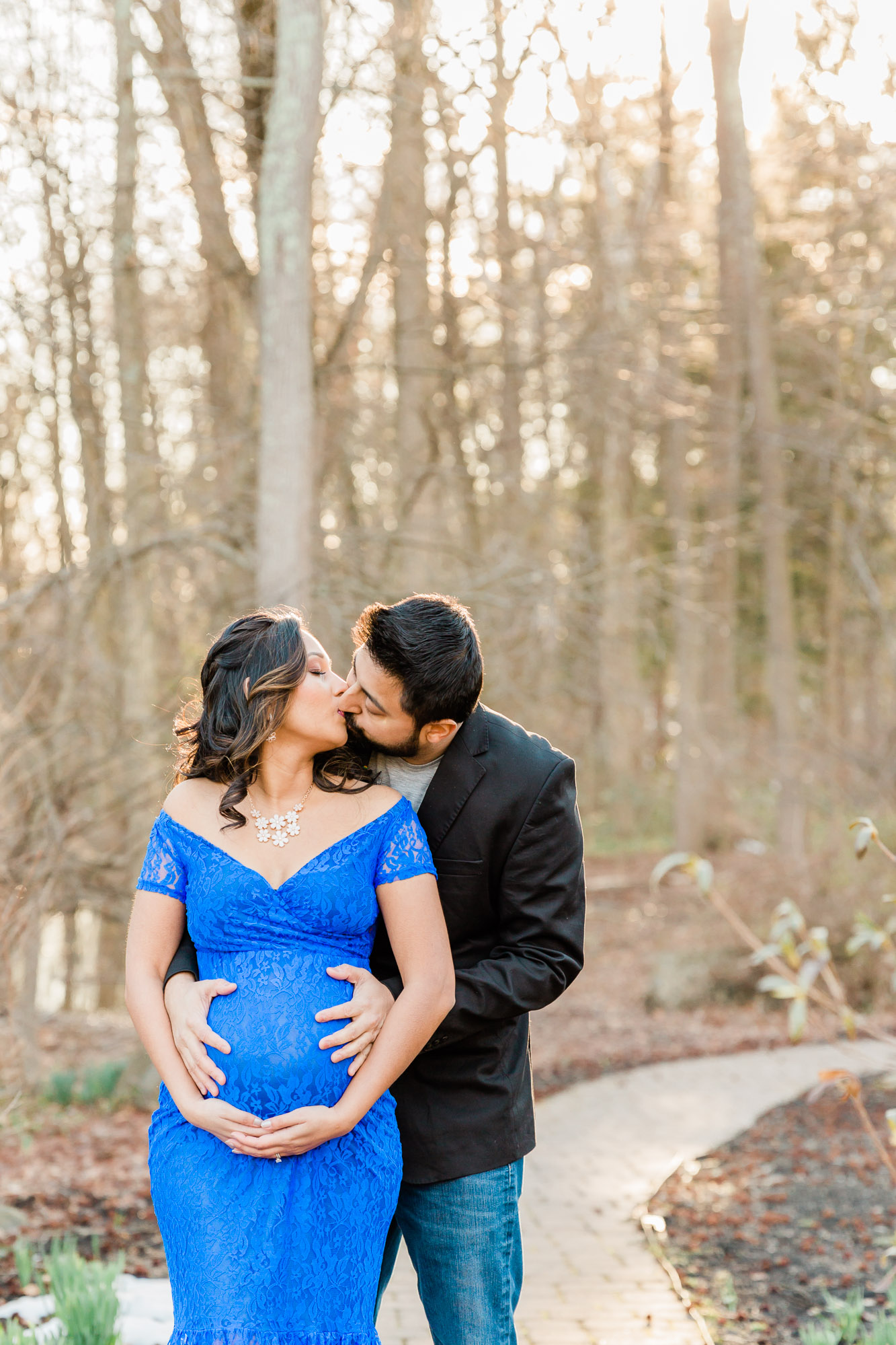 maternity session couple kissing in sun flare